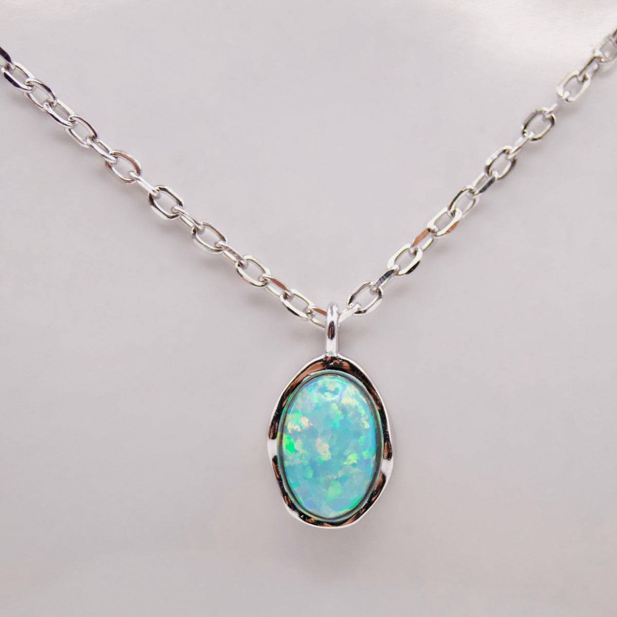 Opal pendant silver necklace on a light background