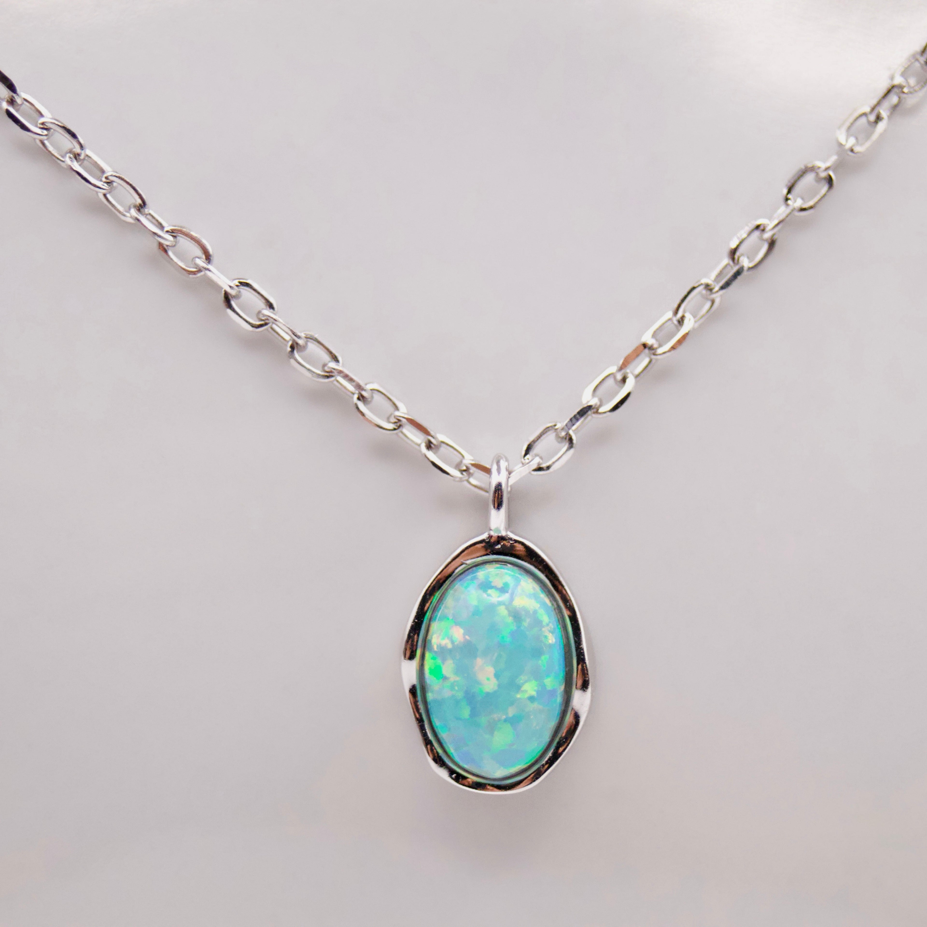 Opal pendant silver necklace on a light background
