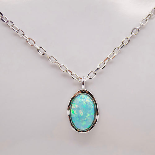 Opal pendant silver necklace on a light background